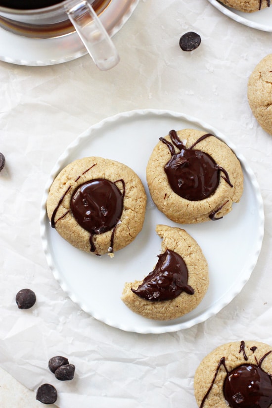 Three Chocolate Peanut Butter Thumbprint Cookies on a plate with a bite taken out of one.