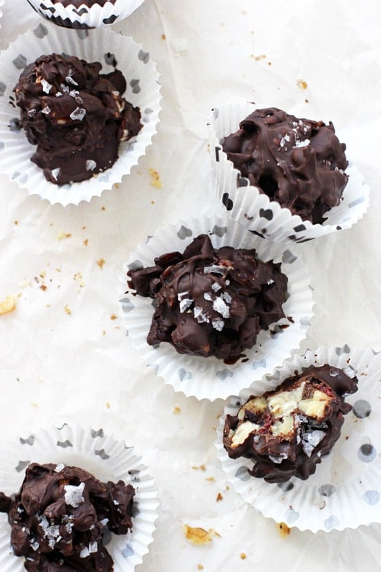 Dark Chocolate Fruit & Nut Clusters in mini muffin liners on white parchment paper.
