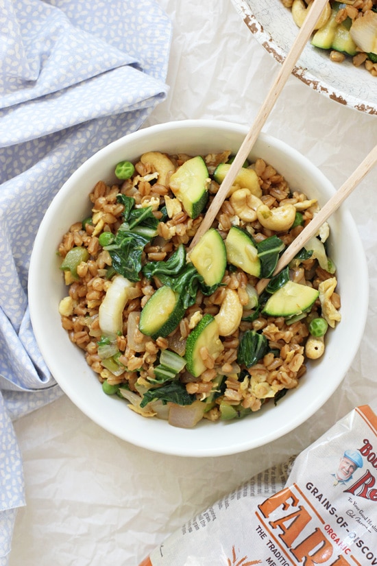 Two bowls of Green Veggie Farro Fried Rice with a bag of farro to the side.