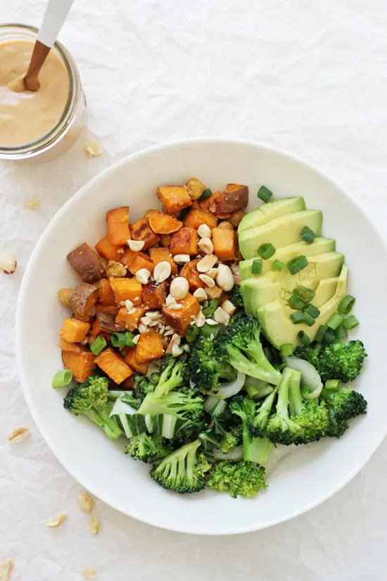 A Peanut Chickpea Sweet Potato Bowl with a jar of peanut sauce in the background.