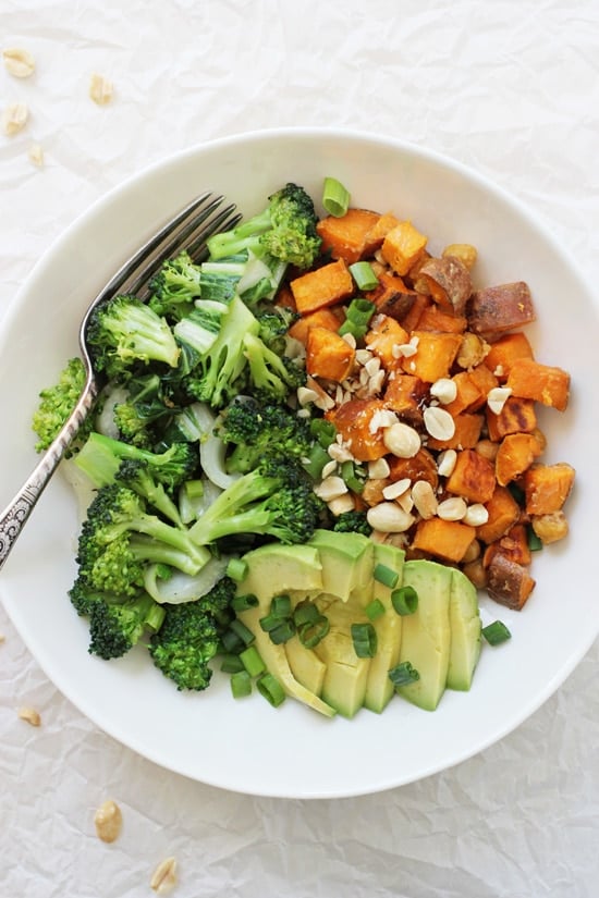 A Peanut Chickpea Sweet Potato Bowl with a fork on white crinkled parchment paper.