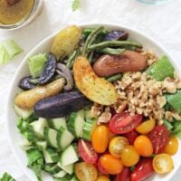 Easy greek salad with roasted vegetables! This healthy dish is packed with fingerling potatoes, green beans, fresh veggies and a flavorful vinaigrette! Serve as a side or as a main topped with a protein of choice!