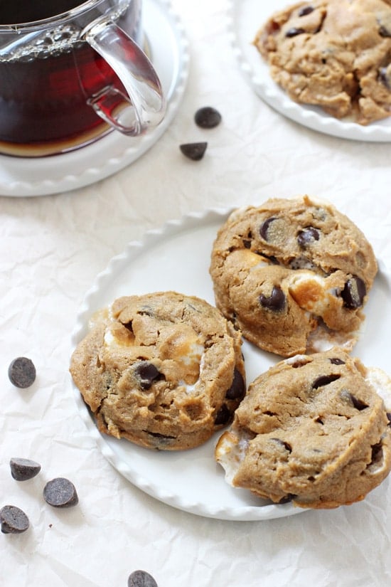 A small white plate with three Flourless Peanut Butter S'mores Cookies and coffee in the background.