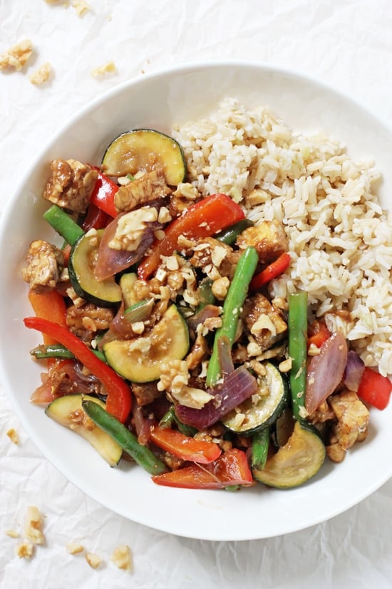 A white bowl filled with Garlic Ginger Summer Veggie Stir-Fry and brown rice.