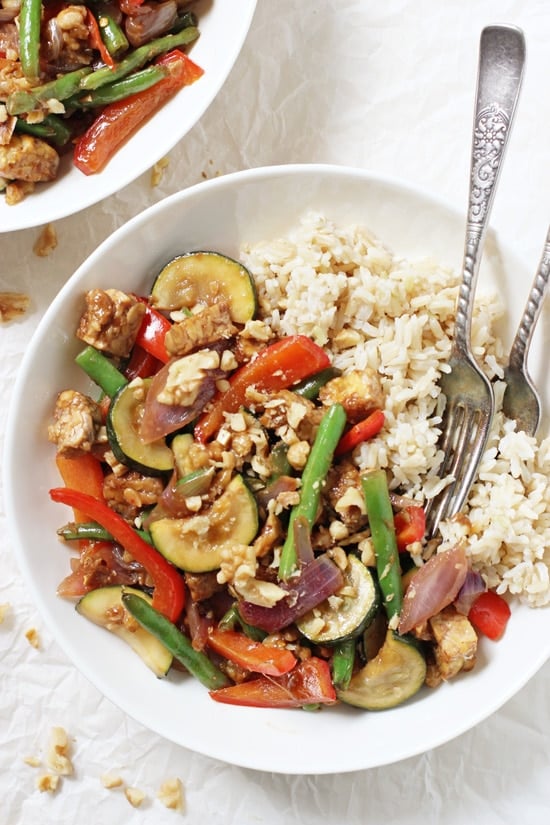 A bowl filled with Garlic Ginger Summer Veggie Stir-Fry and two forks with another bowl in the background.