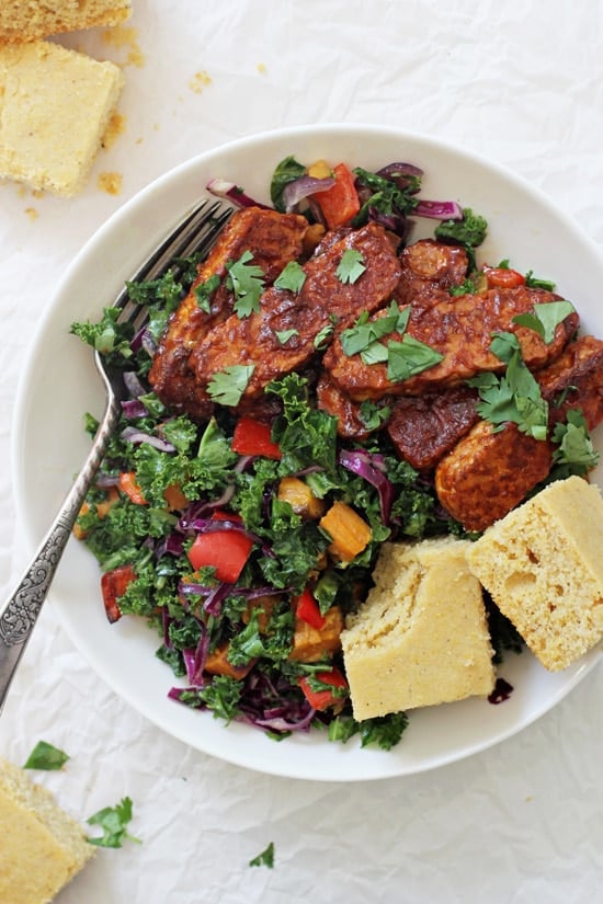 An overhead view of Baked BBQ Tempeh Bowls with a fork and two pieces of cornbread in the bowl.