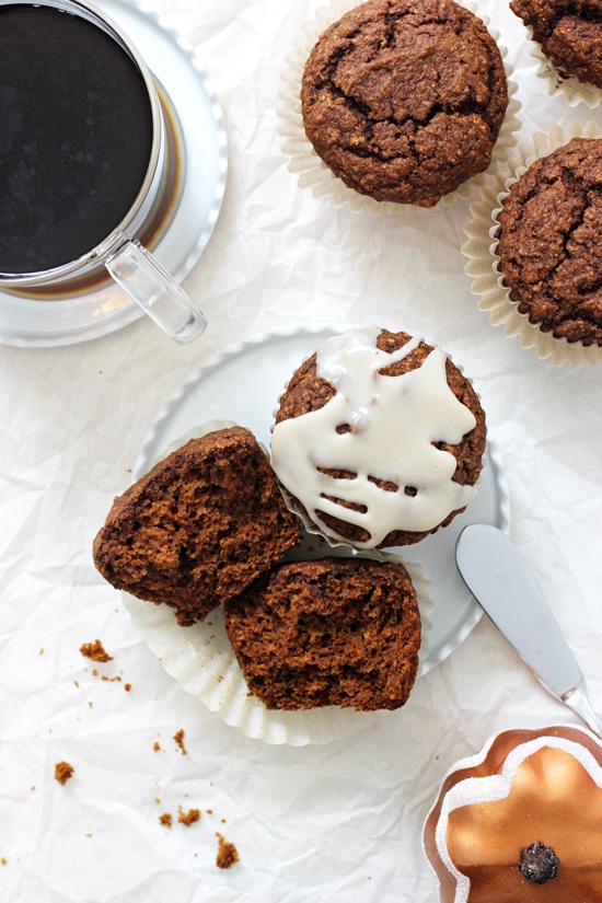 Two Healthy Pumpkin Gingerbread Muffins on a small plate with one split open and more muffins in the background.