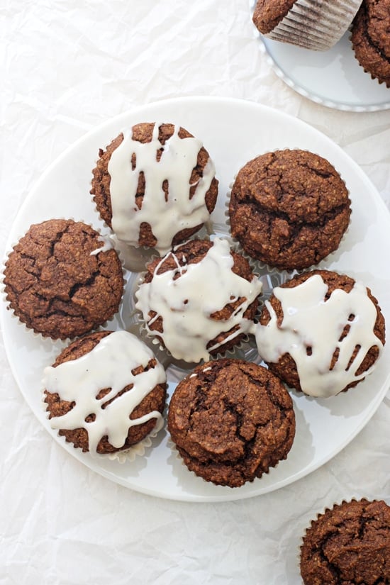 A large plate of Healthy Pumpkin Gingerbread Muffins with more muffins scattered around.