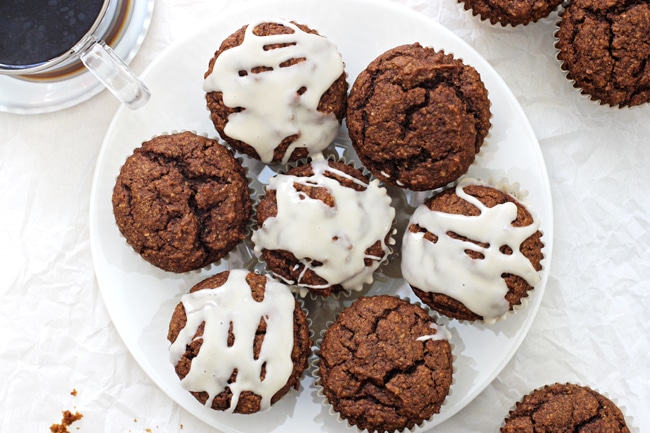A large plate of Pumpkin Gingerbread Muffins with a cup of coffee off to the side.