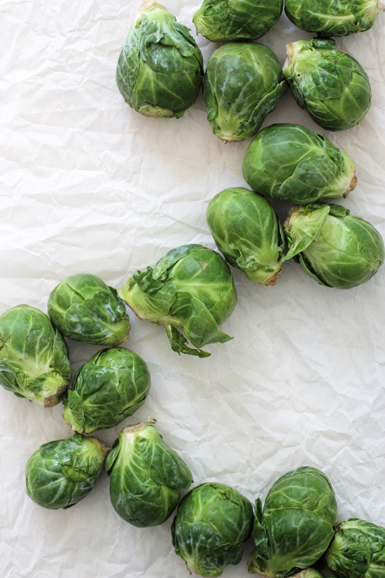 Fresh brussels sprouts scattered on a crinkled piece of white parchment.