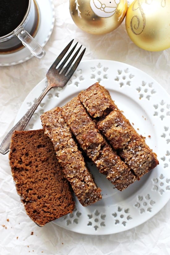 Four slices of Healthy Spiced Sweet Potato Bread on a plate with Christmas ornaments and coffee in the background.