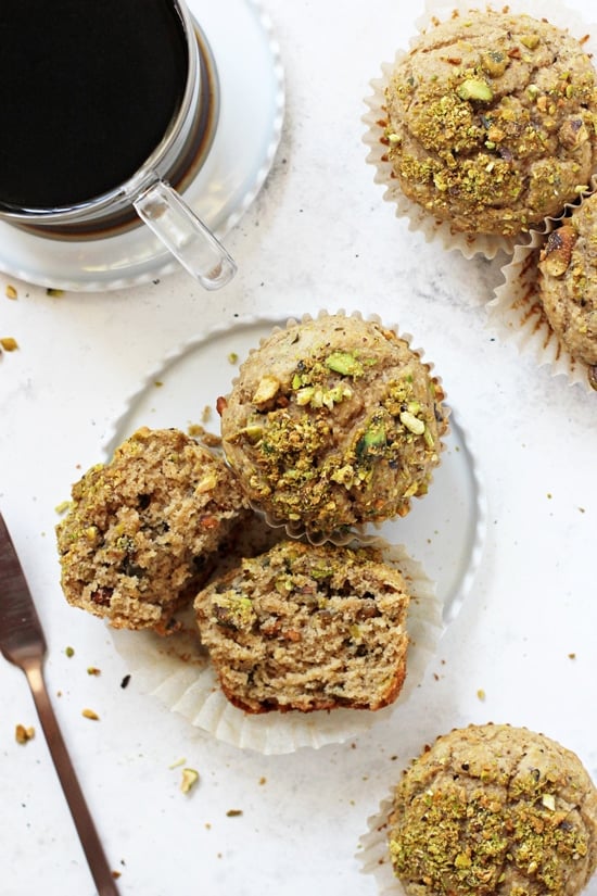 Small white plates with Healthier Pistachio Muffins and black coffee in a mug.