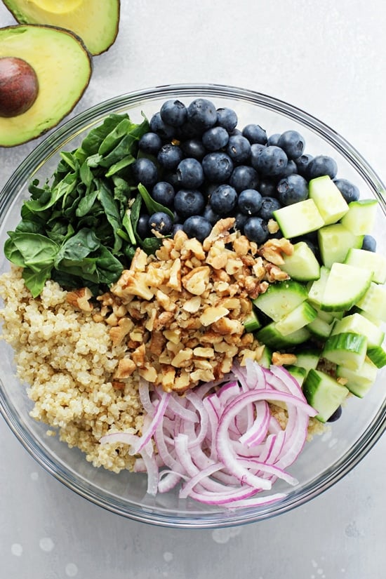 A glass bowl filled with all the components for Berry Quinoa Salad.