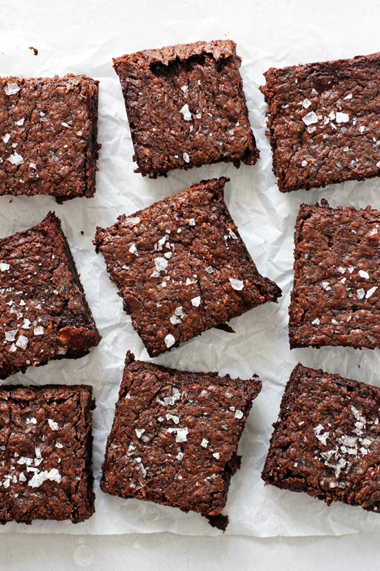 Several Dairy Free Brownies scattered on white parchment paper.