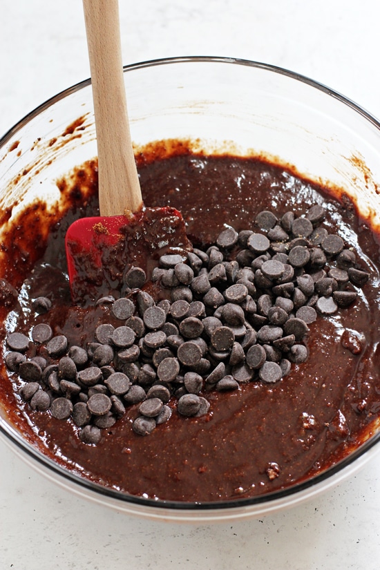 A glass mixing bowl filled with brownie batter and chocolate chips scattered on top.