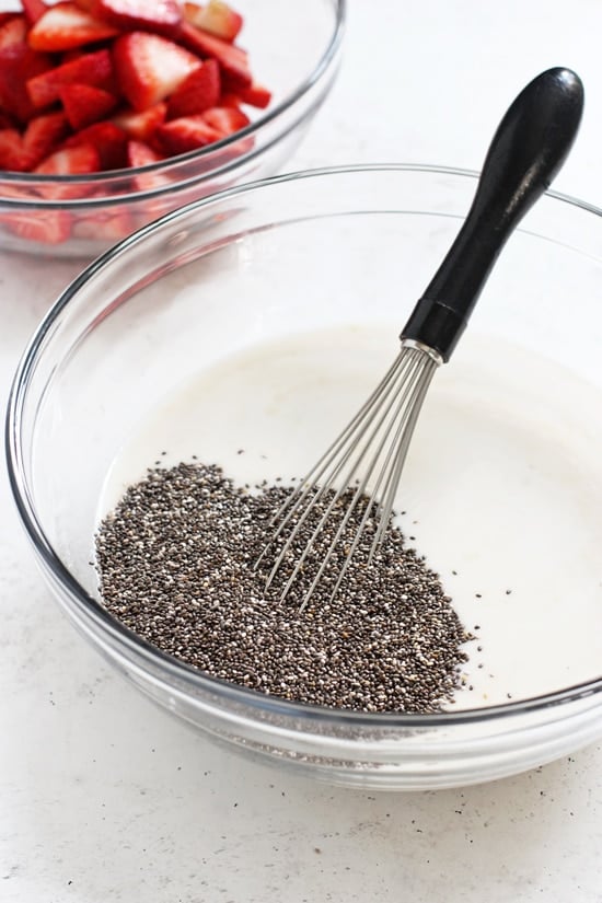 Almond milk and chia seeds in a glass mixing bowl.