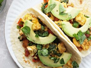 These 25 minute, freezer friendly healthy breakfast tacos are a perfect easy breakfast or dinner! Filled with red onion, bell pepper, scrambled eggs and plenty of spices, plus avocado and salsa for serving. Vegetarian, gluten-free and dairy-free.