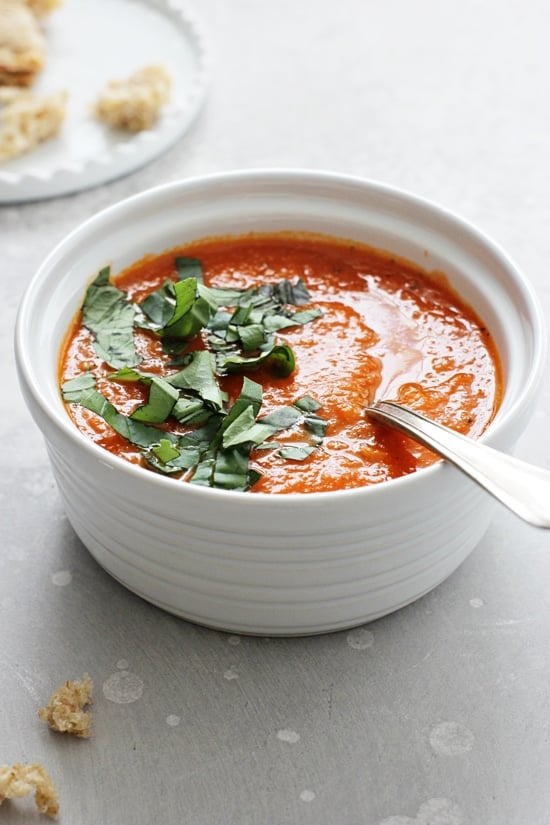 A white bowl filled with Gluten Free Dairy Free Tomato Soup with a spoon in the dish.