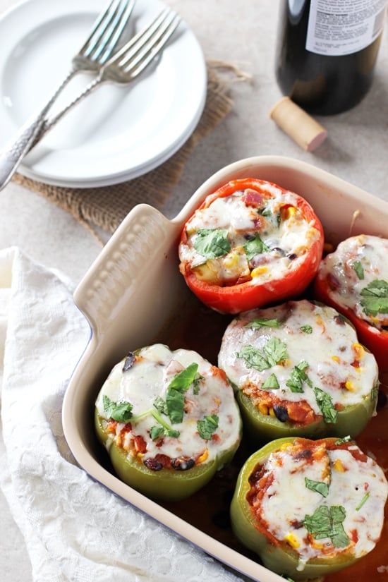 A baking dish filled with Meatless Stuffed Peppers with two plates to the side.