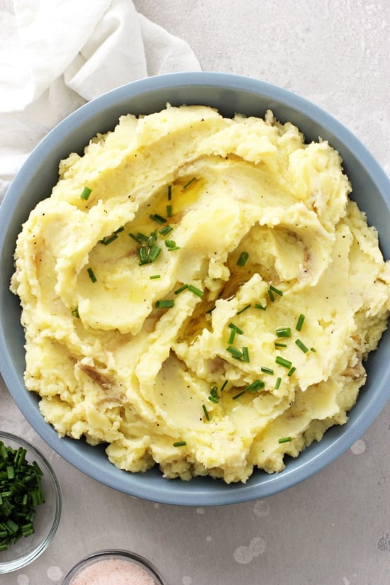 A blue bowl filled with Dairy Free Mashed Potatoes with a napkin to the side.