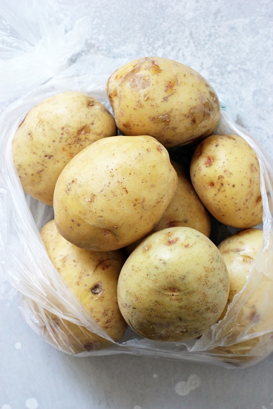 A plastic bag filled with yukon gold potatoes.