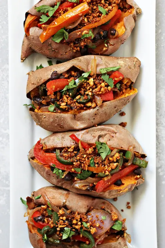 Four Vegan Stuffed Sweet Potatoes lined up on a white platter.