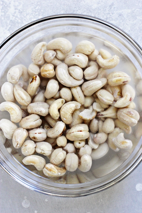 A glass bowl filled with cashews soaking in water.