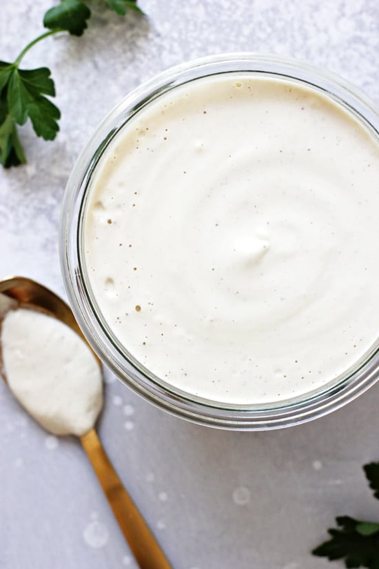Dairy Free White Sauce in a glass jar and a spoon to the side.
