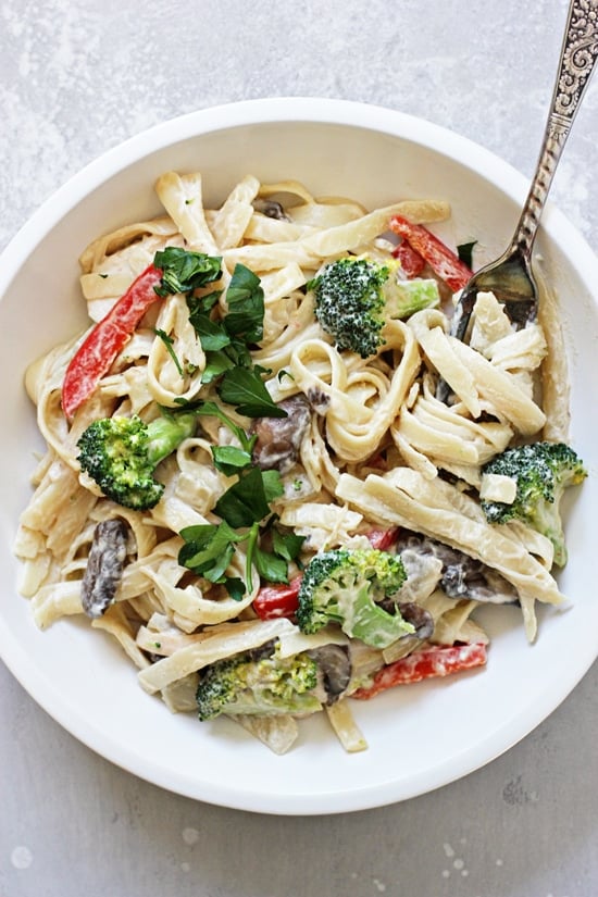 A white bowl filled with Dairy Free Chicken Alfredo and a fork.