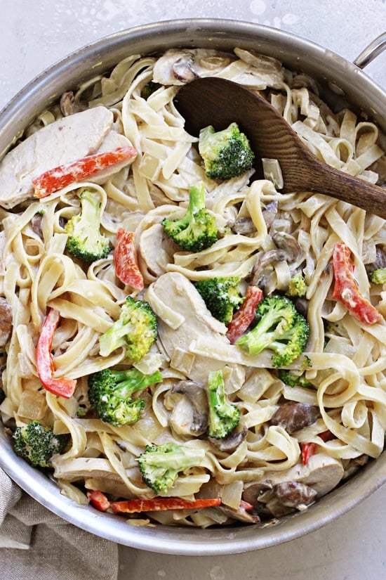 Dairy Free Fettuccine Alfredo in an all-clad skillet with a wooden spoon.