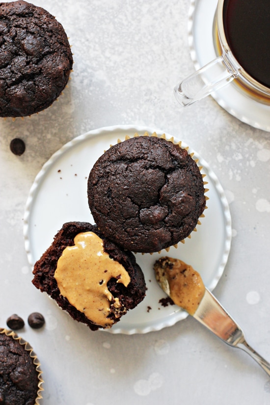 Two Dairy Free Chocolate Chip Muffins on a plate with one smeared with peanut butter.
