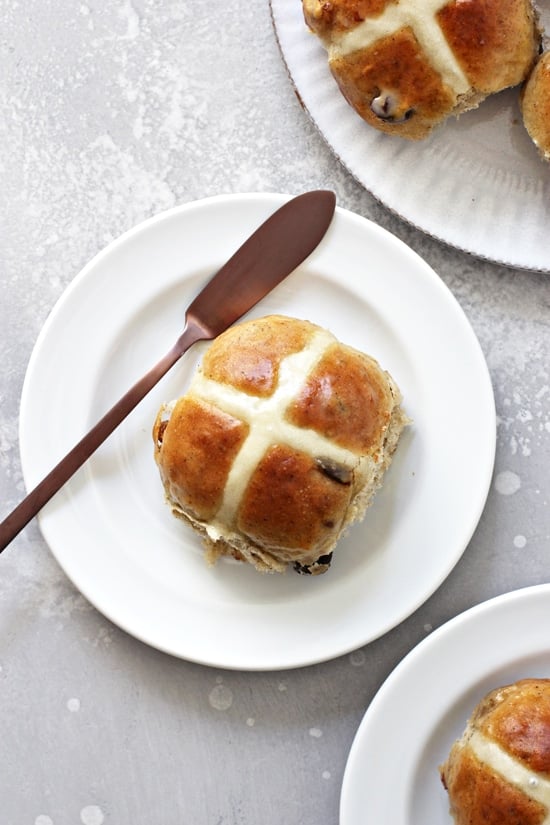 Several Dairy Free Hot Cross Buns on white plates.