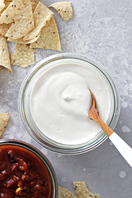 Cashew Sour Cream in a jar with salsa and chips to the side.
