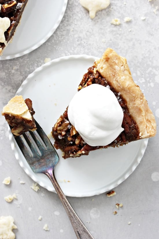 A slice of Vegan Pecan Pie topped with whipped coconut cream.