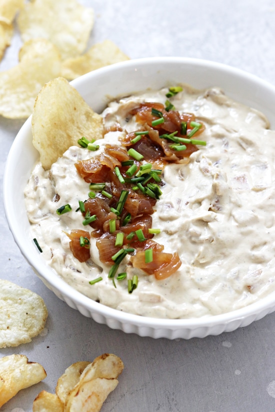 A bowl filled with Non Dairy French Onion Dip with a chip in the dish.