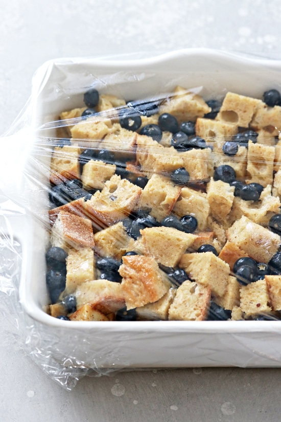 A unbaked french toast casserole covered with plastic wrap.