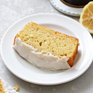 A slice of Dairy Free Lemon Drizzle Cake with coffee to the side.