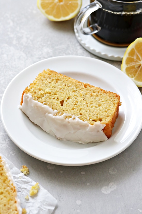 A slice of Dairy Free Lemon Drizzle Cake with coffee to the side.