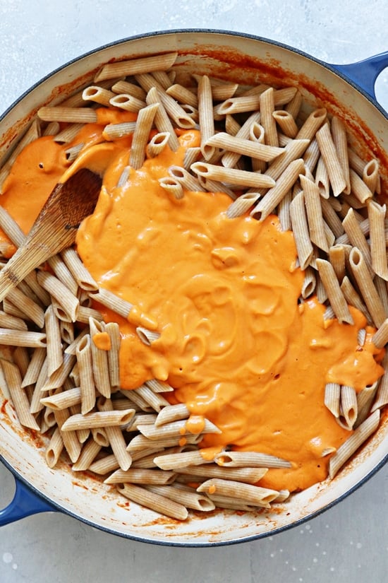 Vodka sauce poured over pasta in a skillet.