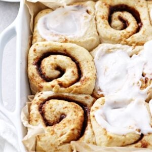 A baking dish filled with partially iced Dairy Free Cinnamon Rolls.