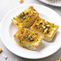 Three slices of Dairy Free Garlic Bread on a white plate.