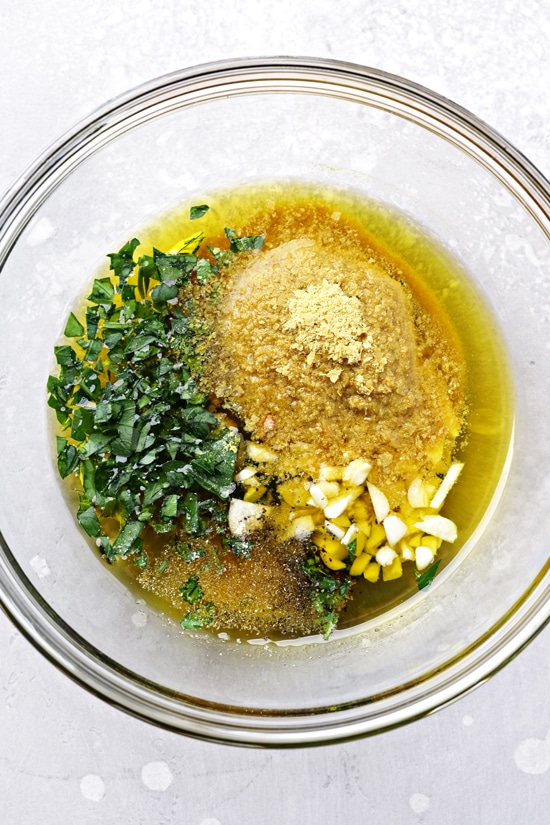 A mixing bowl with olive oil, garlic and spices.