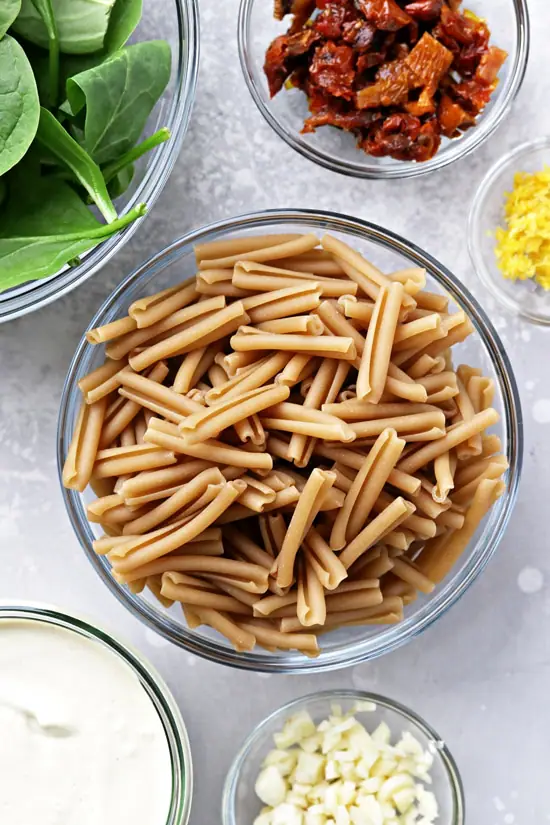 Veggies, sauce and dry pasta in small bowls.