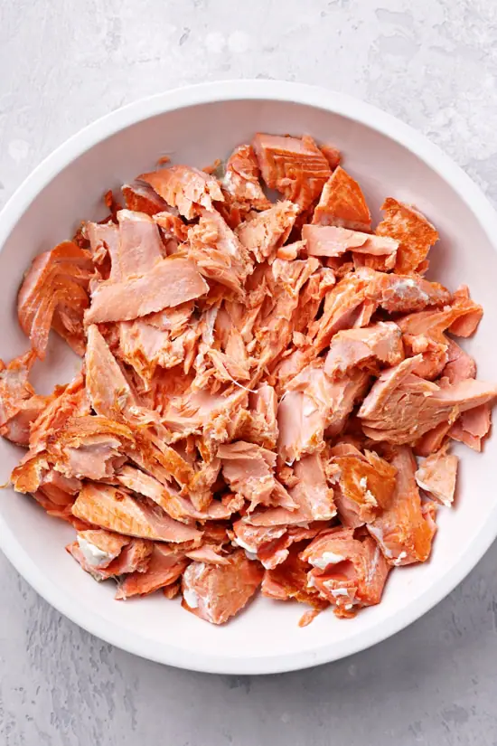 Flaked cooked salmon in a bowl.