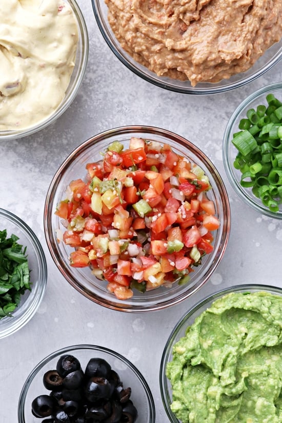 Small bowls filled with salsa, guac and fresh veggies.
