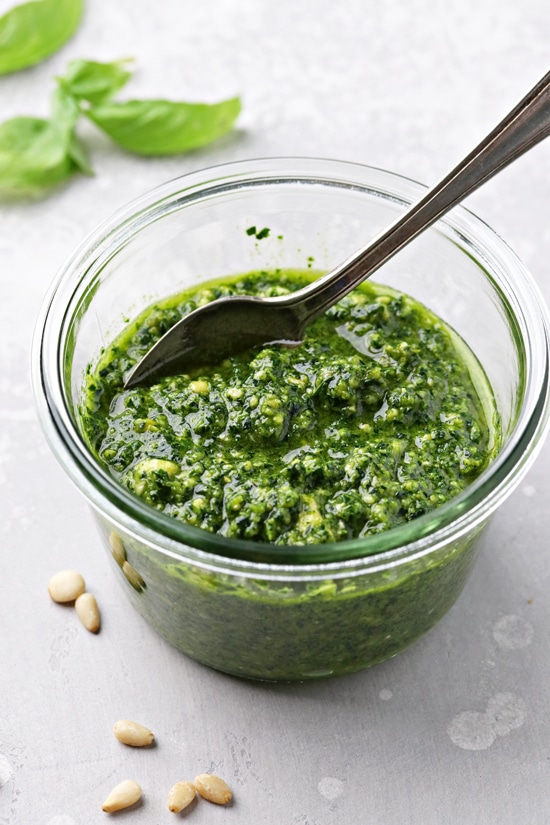 A glass jar filled with Dairy Free Pesto Sauce.