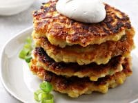 Four Dairy Free Corn Fritters stacked on a plate.