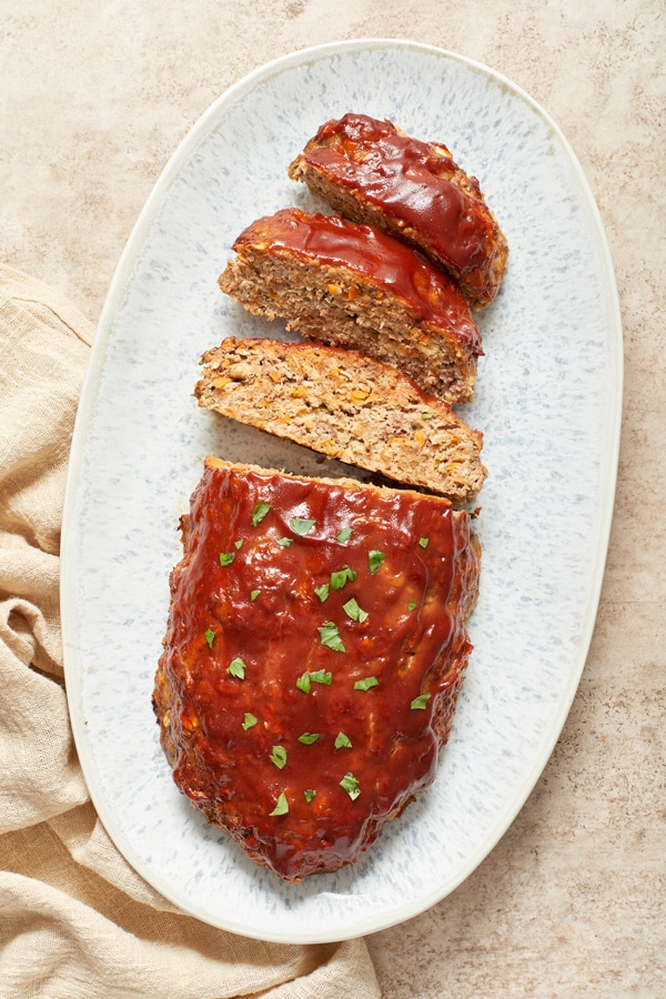 A partially sliced Gluten Free Dairy Free Meatloaf on a platter.