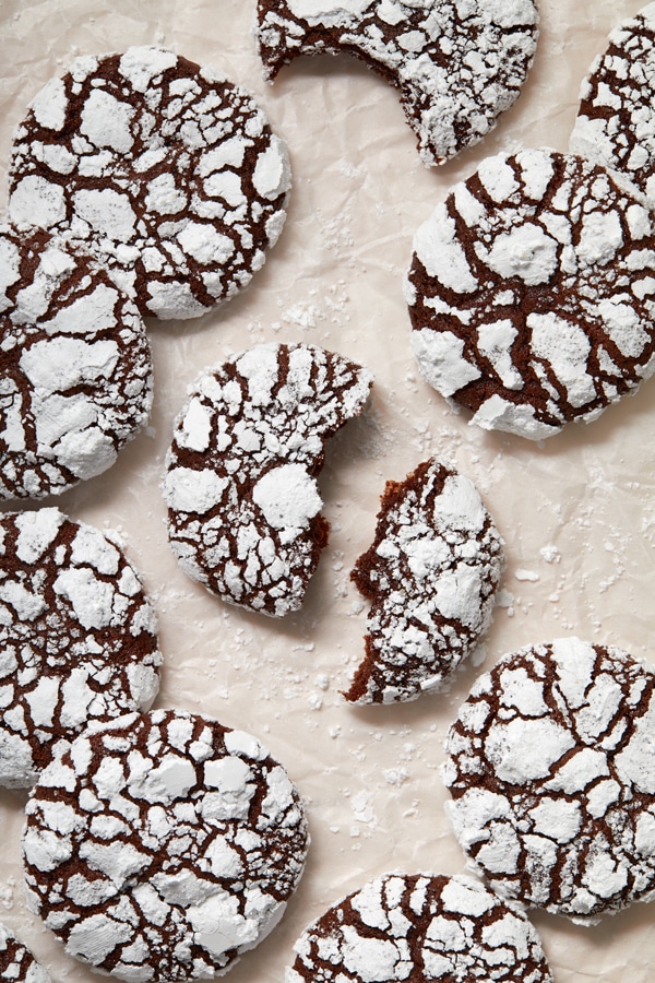 Non Dairy Chocolate Crinkle Cookies on parchment with one split in half.