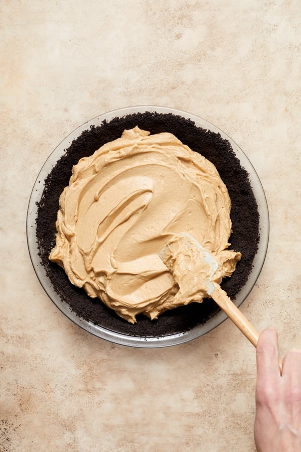 Peanut butter filling being spread in a cookie crust.